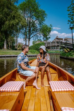 Giethoorn Hollandalı çift, sıcak bir bahar günü çiftlikte, kanallı ve sazdan çatı evleriyle ünlü köy manzaralı bir tekneyle köyü ziyaret ediyor.