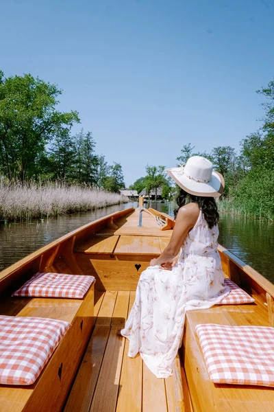 Giethoorn Netherlands woman visit the village with a boat, view of famous village with canals and rustic thatched roof houses in farm area on a hot Spring day — стоковое фото