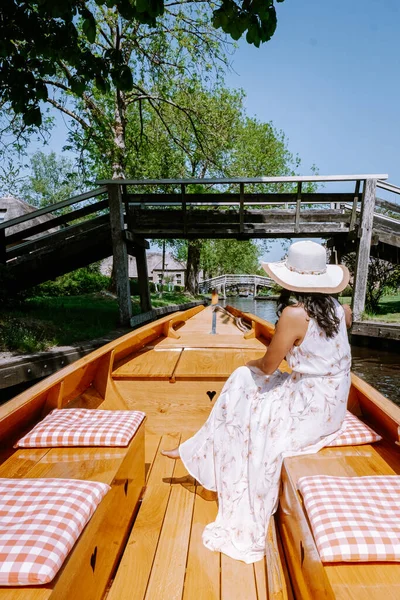 Giethoorn Países Bajos mujer visita el pueblo con un barco, vista de la famosa aldea con canales y casas de techo de paja rústica en la zona de la granja en un día de primavera caliente — Foto de Stock