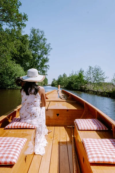 Giethoorn Netherlands woman visit the village with a boat, view of famous village with canals and rustic thatched roof houses in farm area on a hot Spring day — стоковое фото