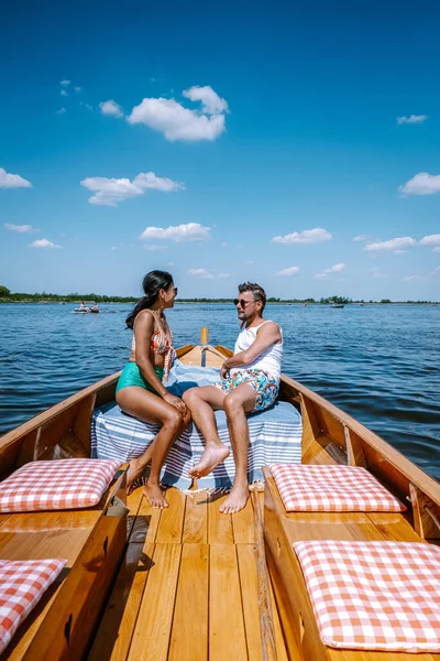 Giethoorn Nederland echtpaar bezoek het dorp met een boot, uitzicht op beroemde dorp met grachten en rustieke rieten daken in de boerderij op een warme Lente dag — Stockfoto