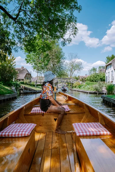 Giethoorn Holanda mulher visitar a aldeia com um barco, vista da famosa aldeia com canais e casas de telhado de palha rústica na área da fazenda em um dia de primavera quente — Fotografia de Stock