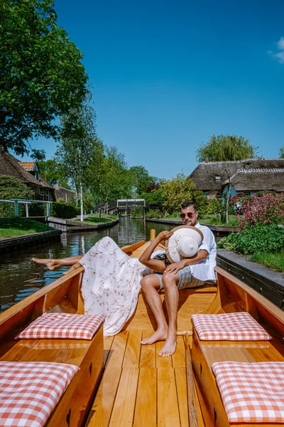 Giethoorn pareja holandesa visita el pueblo con un barco, vista del famoso pueblo con canales y casas rústicas con techo de paja en la zona de la granja en un día de primavera caliente — Foto de Stock