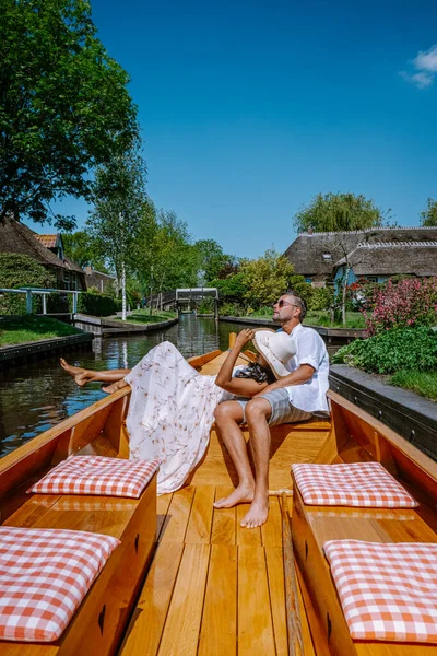 네덜란드에 사는 지오토온 부부는 배를 타고 마을 을방 문하면서, 어느 더운 봄날 농장 지역에 운하와 소박 한 초가지 붕 집들이 있는 유명 한 마을을 바라본다 — 스톡 사진