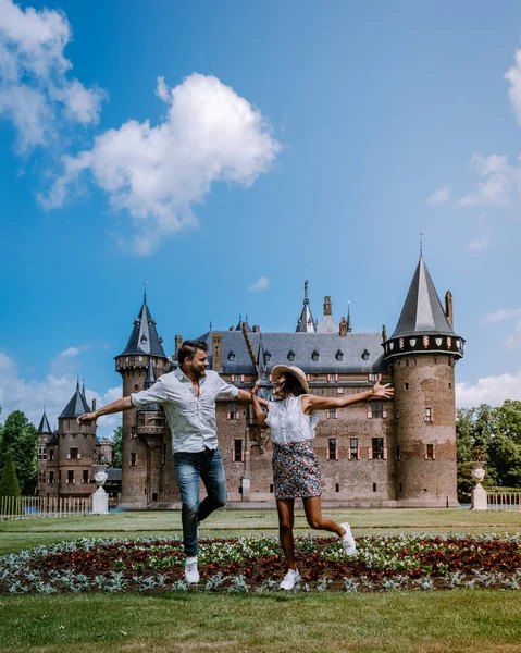 Pareja de hombres y mujeres visitan un castillo en los Países Bajos, Castillo de Haar Países Bajos Utrecht en un brillante, joven pareja de hombres y mujeres de mediana edad caminando en el jardín del castillo — Foto de Stock