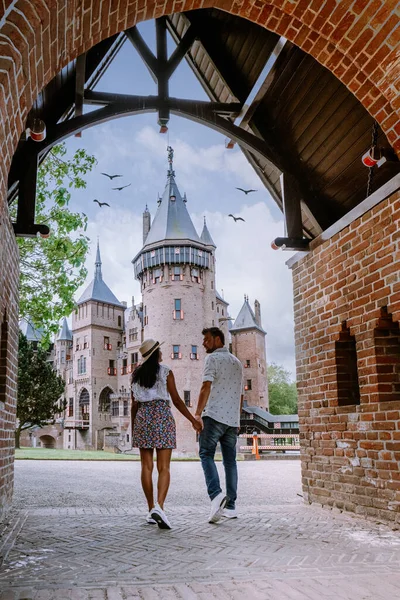 Pareja de hombres y mujeres visitan un castillo en los Países Bajos, Castillo de Haar Países Bajos Utrecht en un brillante, joven pareja de hombres y mujeres de mediana edad caminando en el jardín del castillo — Foto de Stock