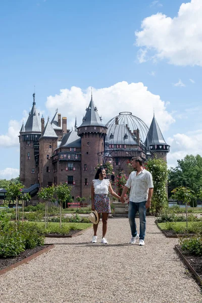 Viejo jardín histórico del castillo, Castillo de Haar Países Bajos Utrecht en un día de verano brillante, joven pareja de hombres y mujeres de mediana edad caminando en el jardín del castillo — Foto de Stock