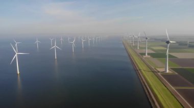 Yel değirmeni parkı Batı Hollanda, rüzgâr değirmeni türbini okyanusta mavi gökyüzü, yeşil enerji