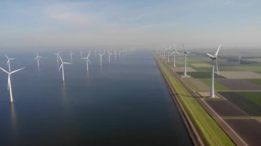 Yel değirmeni parkı Batı Hollanda, rüzgâr değirmeni türbini okyanusta mavi gökyüzü, yeşil enerji