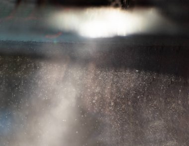 Güneş tarafından dövülen küçük su damlaları gri soyutlamalar oluşturur.