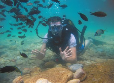 Donanımlı bir çocuk, Antalya 'daki Akdeniz' in mavi sularındaki berrak sularda çok sayıda balıkla çevrili bir şekilde dalıyor..                   