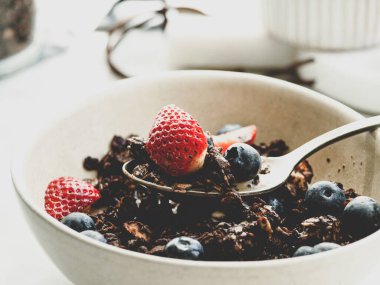 Kahvaltı kâsesi granola ve beyaz arka planda böğürtlen.