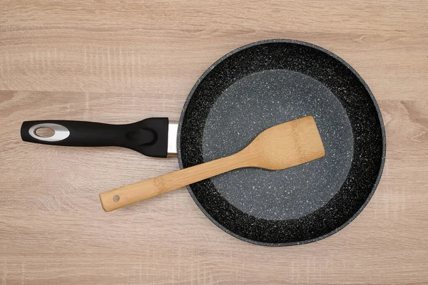 Μαύρο Στρογγυλό Τηγάνι Ξύλινη Σπάτουλα Κουζίνα Ξύλο Απομονωμένα Πιάτα Μαγείρεμα — Φωτογραφία Αρχείου