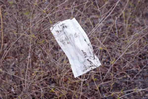 dirty, abandoned, medical, protective mask hanging on a bush. Coronavirus, Covid-19, Quarantine.