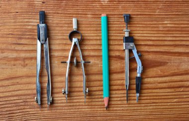 İki metal bölme, metal çizim pusulası ve ahşap zemin üzerinde izole yeşil kalem içeren çizim araçlarının yakın çekim seti