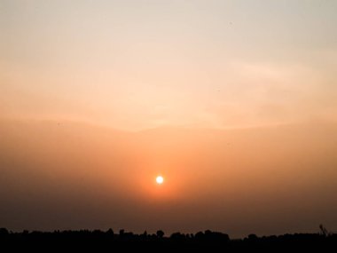 Gün batımında Hindistan köyü tarım arazisi, güneş ışığı ve güzel gökyüzü.