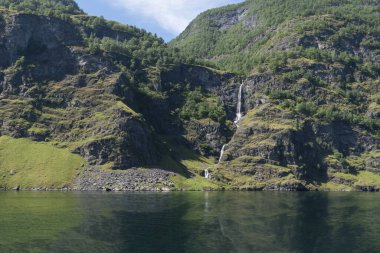 Göl kenarında şelalesi olan bir dağ manzarası