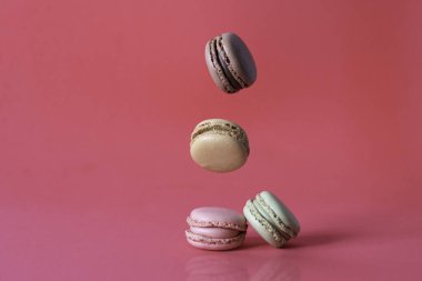 Tatlı Fransız kurabiyeleri kırmızı arka planda hareket ediyor. Pastel renkli uçan kurabiyeler. Yemek ve aşçılık..