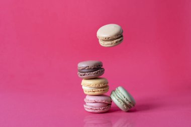 Tatlı Fransız kurabiyeleri kırmızı arka planda hareket ediyor. Pastel renkli uçan kurabiyeler. Yemek ve aşçılık..