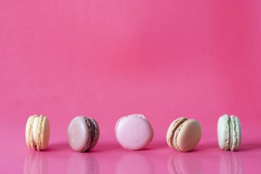 Pembe arka planda izole edilmiş taze renkli makarnaları kapatıyoruz. Tatlı renkli bisküviler masaya yansıyan yansımayla aynı hizaya getiriliyor.