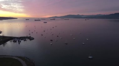 Bir kargo gemisi, yat ve yat ile gün batımında English Bay 'in üzerinden uçun.