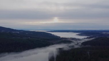 Fly towards the morning sun in clouds with the forest covered with fog behind
