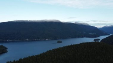 River with a small island in the center and mountains covered with the snow behind
