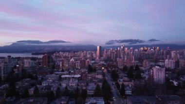 Vancouver şehir merkezinde ve arka planda dağlar, gün batımında.