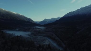 Vadinin ve vahşi Kanada ormanının açılışı. Ortasında nehir, alçak bulutlar ve etrafındaki dağlar.