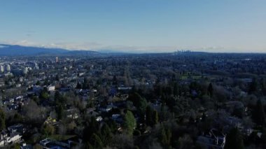 Ufukta yeşil ağaçlar ve evlerle Vancouver manzarasının üzerinden uç.