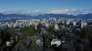 Vancouver 'ın şehir merkezindeki karlı dağların arkası ve önünde yeşil ağaçların olduğu yakın çekim.