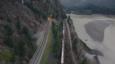 Fraser nehrinin yakınındaki dağdaki tünele giden trenin üzerinden uç.