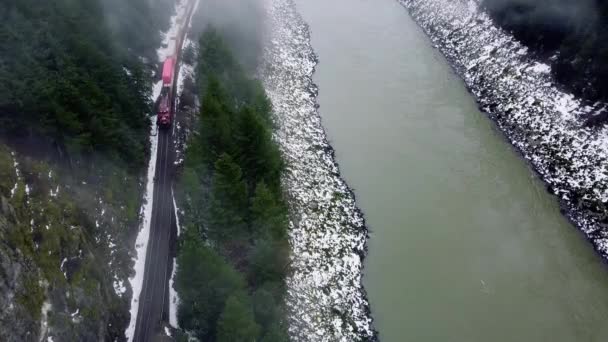 片側の山とゆっくりと動く川と共に鉄道と列車を飛び越える — ストック動画