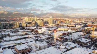Vancouver Olimpiyat Köyü 'nün sarı gün batımı ışığı. Çatıları karla kaplı ve birkaç bina var.