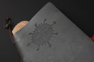 gray leather-bound diary with a compass on a black background clipart
