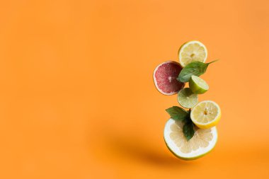 Turuncu arka planda fesleğen yapraklı portakal, limon ve limon. Citrus.