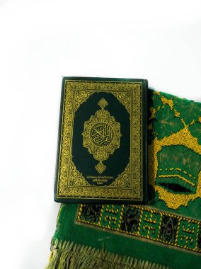 Endonezya 'da. 20 Nisan 2020. Kuran 'ın fotoğrafları ve dua halıları Ramazan ayı için hazır. Kapaktaki Arapça Kuran olarak tercüme edilir.