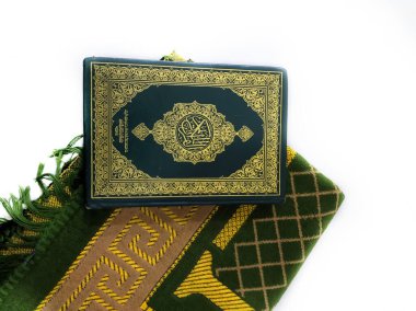 Endonezya 'da. 20 Nisan 2020. Kuran 'ın fotoğrafları ve dua halıları Ramazan ayı için hazır. Kapaktaki Arapça Kuran olarak tercüme edilir.