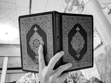 Endonezya 'da. 20 Nisan 2020. Kuran okuyan adamın fotoğrafı Ramazan ayı için hazır. Arapça bir Kur 'an ki, onda Arapça bir sure vardır.