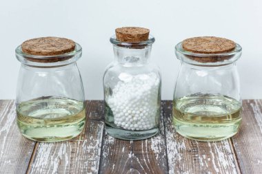 Klasik Homeopati küreleri ve ahşap arka planda klasik cam şişeler. Alternatif Homeopati ilaç şifalı bitkiler, sağlık sigortası ve hap konsepti. Metin için yer.