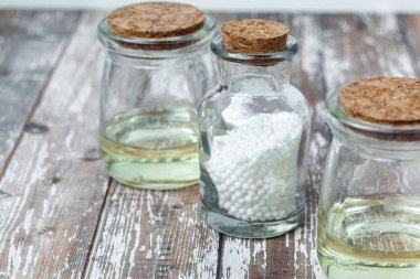Klasik Homeopati küreleri ve ahşap arka planda klasik cam şişeler. Alternatif Homeopati ilaç şifalı bitkiler, sağlık sigortası ve hap konsepti. Metin için yer.