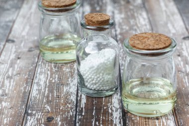Klasik Homeopati küreleri ve ahşap arka planda klasik cam şişeler. Alternatif Homeopati ilaç şifalı bitkiler, sağlık sigortası ve hap konsepti. Metin için yer.