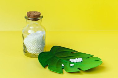 Klasik Homeopati küreleri ve sarı arka planda klasik cam şişeler. Alternatif Homeopati ilaç şifalı bitkiler, sağlık sigortası ve hap konsepti. Metin için yer.