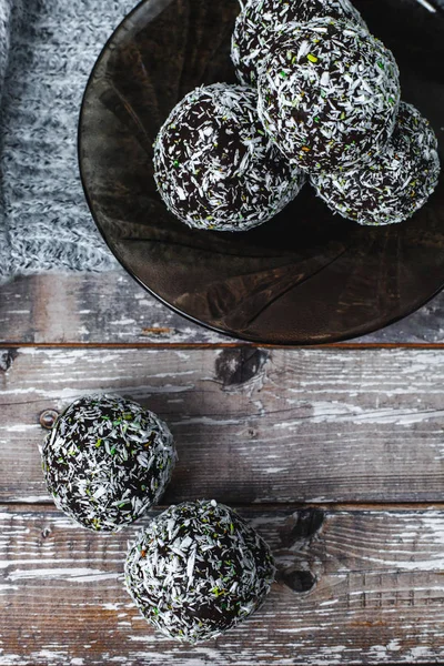 rum chocolate balls with coconut flakes on tray. Sweet raw vegan balls. Chocolate, coconut, dates and banana. Wooden background. Healthy lifestyle.