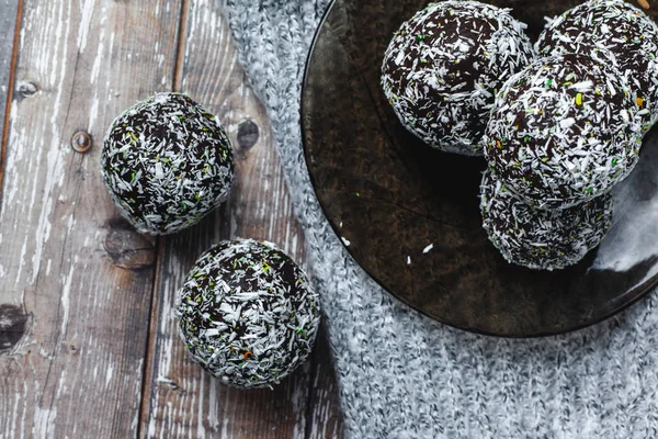 rum chocolate balls with coconut flakes on tray. Sweet raw vegan balls. Chocolate, coconut, dates and banana. Wooden background. Healthy lifestyle.