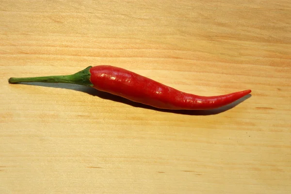 Fotografia de uma pimenta vermelha fresca em um tabuleiro de madeira para ilustração de alimentos — Fotografia de Stock