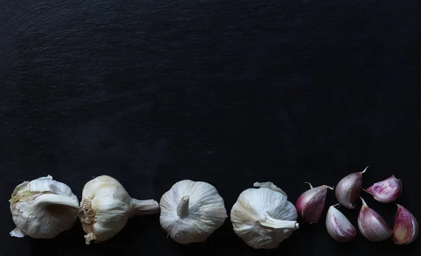 Photography of garlic heads and cloves on slate background for restaurant menu or market sign