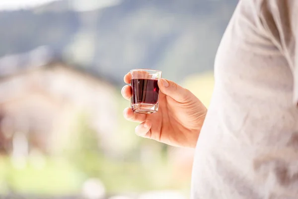man holding red alcohol shot in a small glass on a celebration
