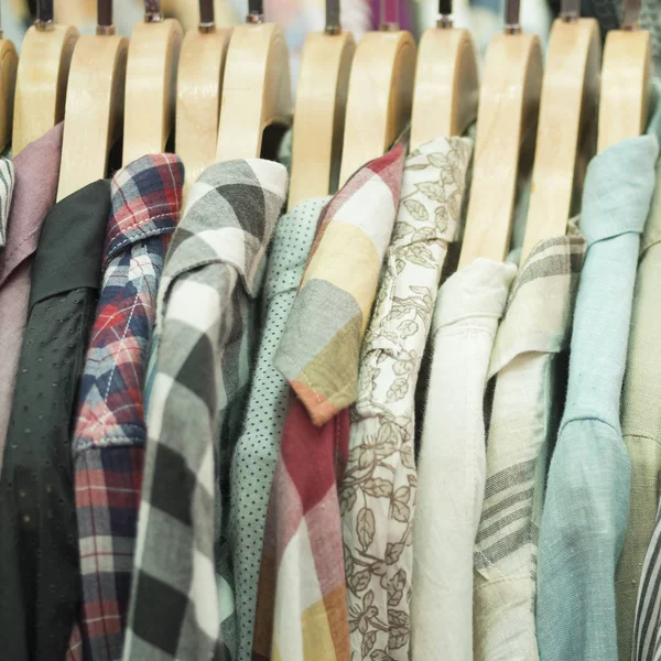 Selection of men\'s shirts hanging inside a wardrobe