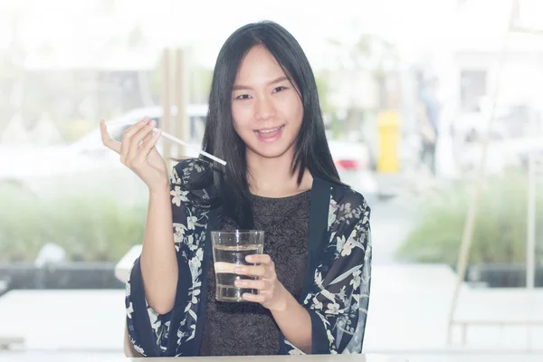 亚洲女人微笑着对新鲜水玻璃的肖像. — 图库照片